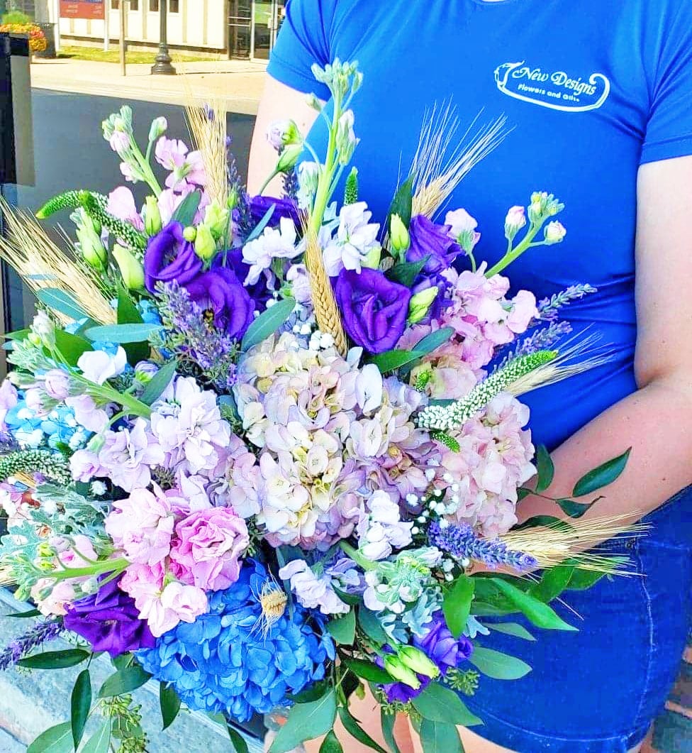 A stunning bouquet of ombre Pink Purple and Blue Hydrangeas and Stock, with wheat stems spiking through
